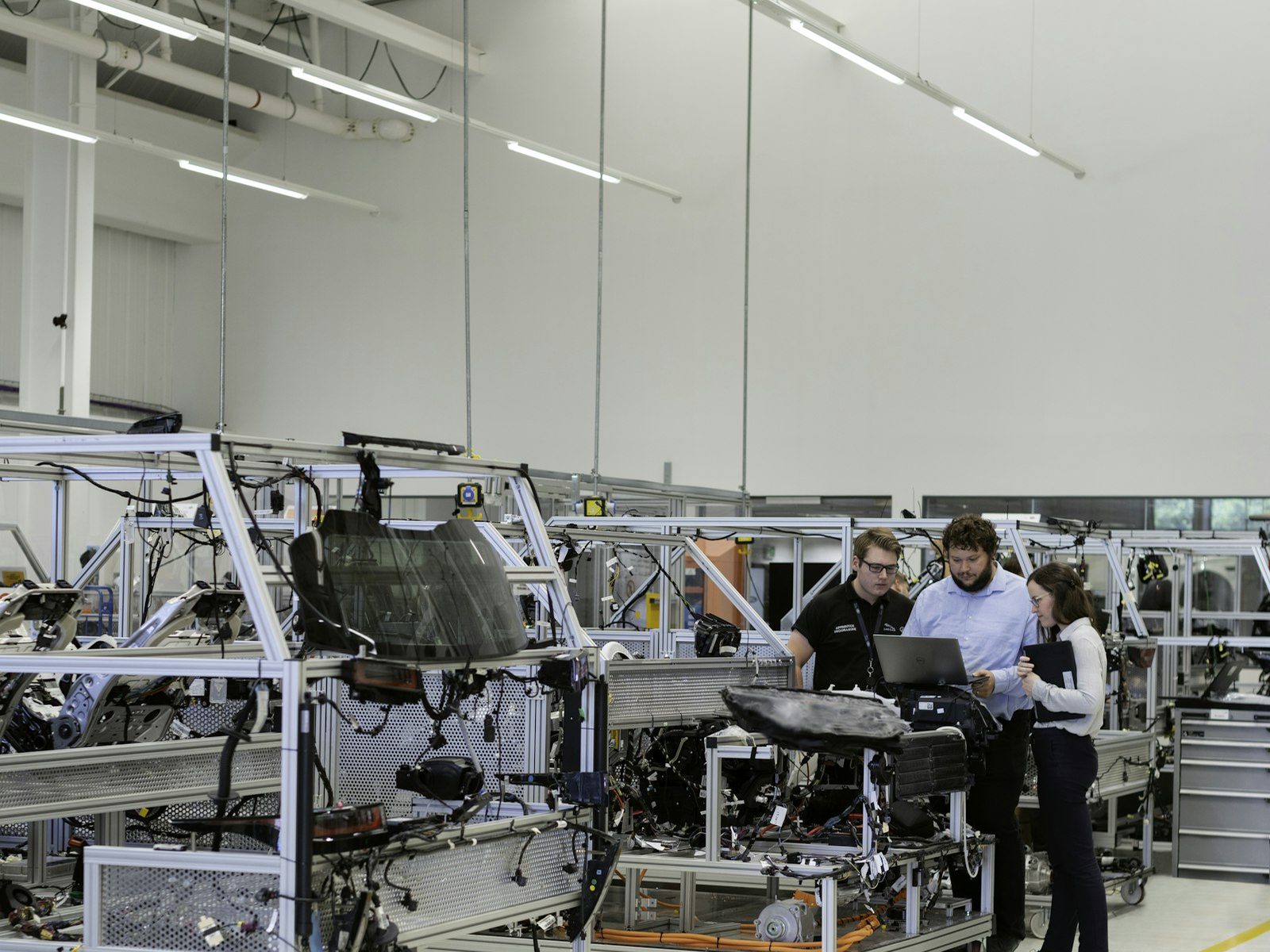 Two engineers in high-visibility vests inspecting components on a manufacturing floor.