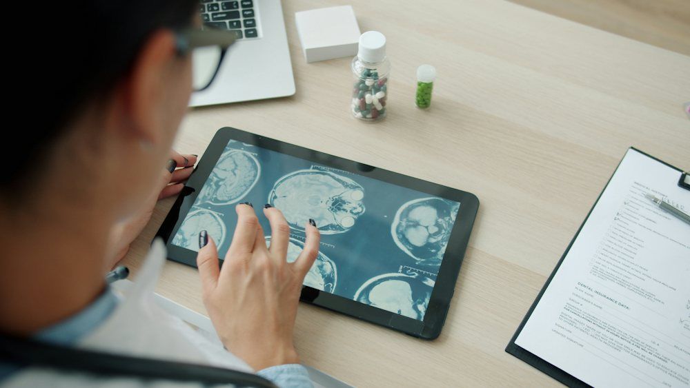 A doctor reviewing MRI scans on a tablet at a desk